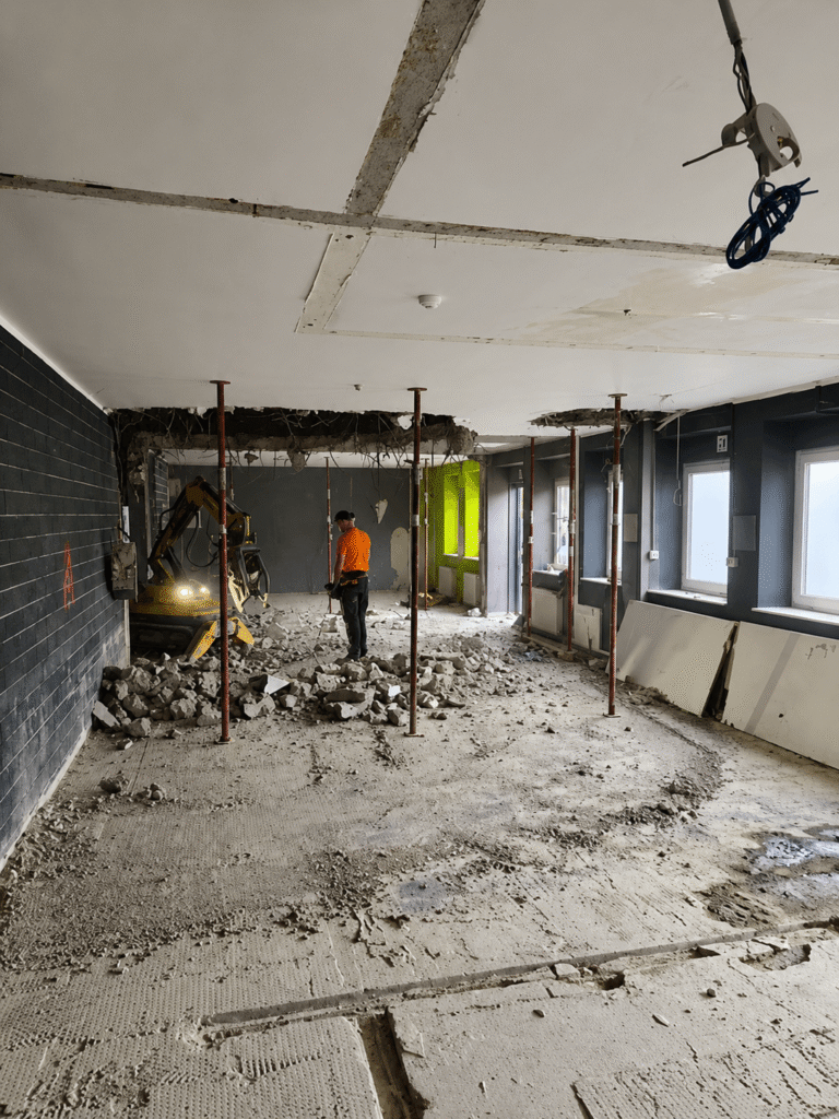 Mitarbeiter und Abbruchroboter beim selektiven Rückbau in einem abgestützten Bestandsgebäude in Aachen.