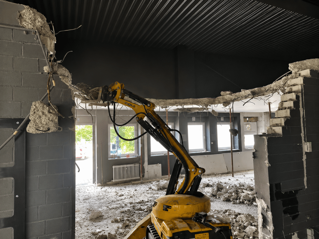Ferngesteuerter Abbruchroboter entfernt kontrolliert Teile einer Stahlbetondecke und Innenwände bei Rückbauarbeiten in Aachen.