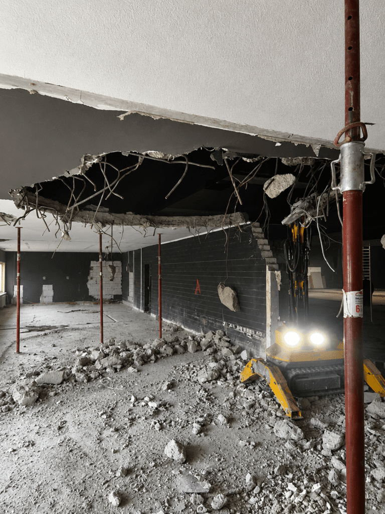 Abbruchroboter beim kontrollierten Rückbau einer Stahlbetondecke mit freiliegender Bewehrung in einem Bestandsgebäude in Aachen.